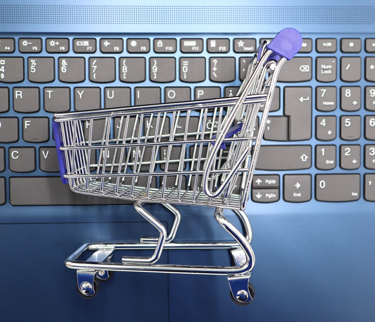 why-choose-us A miniature shopping cart placed on a laptop keyboard symbolizing online shopping and e-commerce.